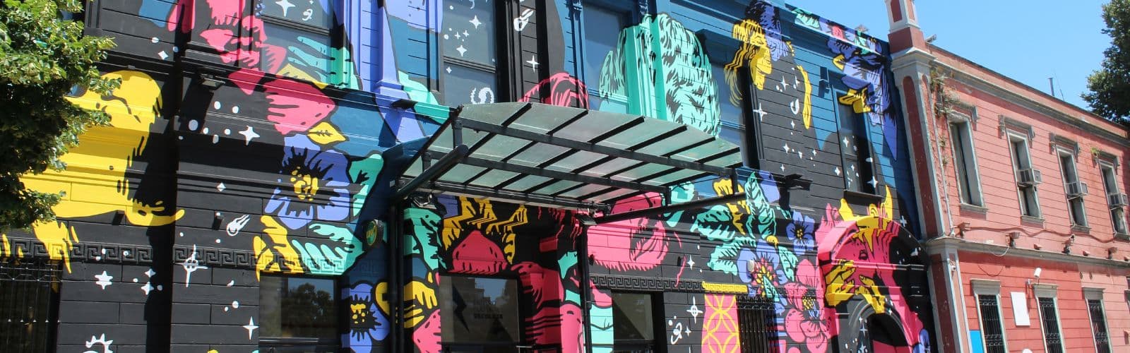 A black building is painted with colorful flowers and other art. 